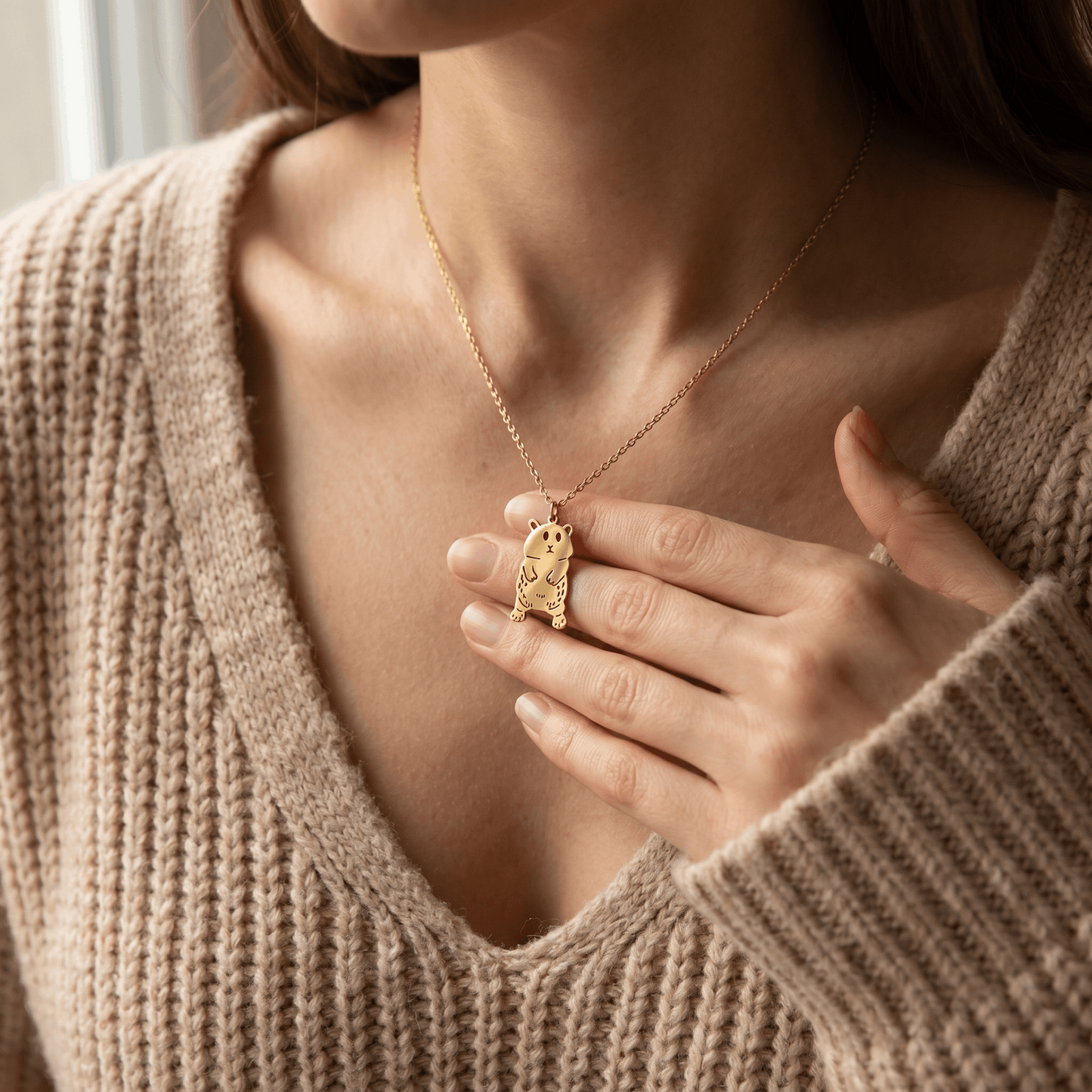 Frau im beigen Strickpullover trägt goldfarbene Kinderzeichnung-Halskette mit ausgestanztem Tier-Anhänger aus Edelstahl